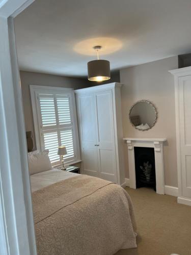 a bedroom with a bed and a mirror and a fireplace at The Lily Pad - Boutique Townhouse, a short walk to Town Center and Racecourse in Cheltenham