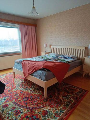 a bedroom with a bed with a rug and a window at Iso kolmio, mahtavalla jokinäkymällä in Joensuu