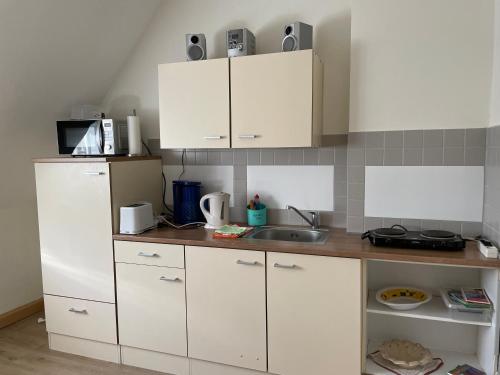 eine Küche mit weißen Schränken und einem Waschbecken in der Unterkunft Pension Evi in Chemnitz