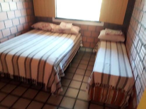 Duas camas num pequeno quarto com uma janela em Flat260 Beira Mangue Mar ar piscinas estac zelador em Itamaracá