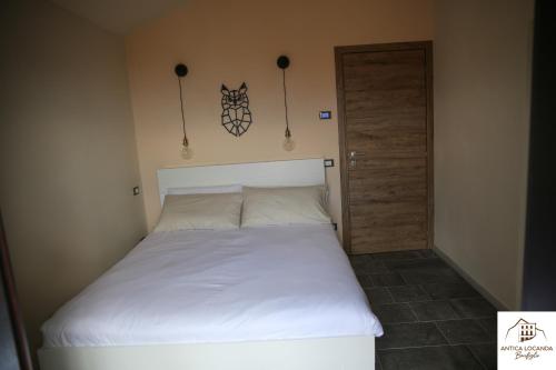 a bedroom with a white bed and a door at Antica Locanda Bonfiglio in Busana