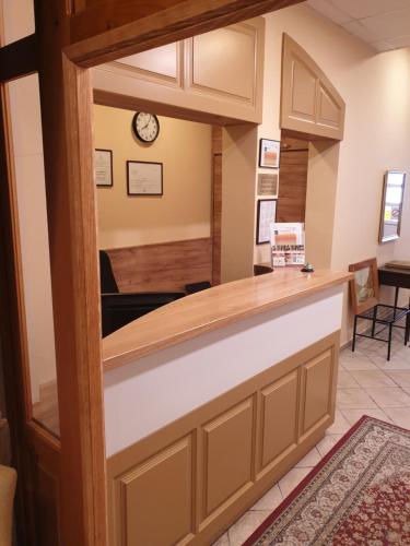 a reception counter in a waiting room with a clock at Art Garni Hotel in Kanjiža