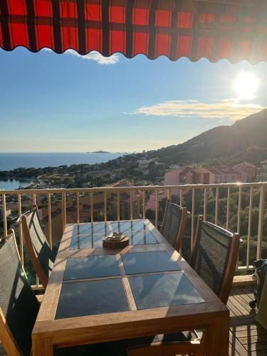 une table en bois sur un balcon avec vue sur l'océan dans l'établissement Super appartement vue Sanguinaires, à Ajaccio