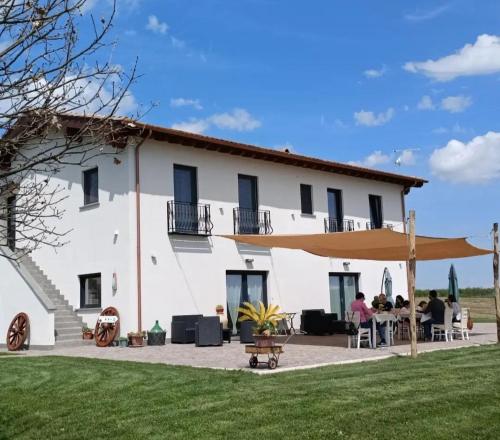 uma grande casa branca com pessoas sentadas em mesas à frente dela em Agriturismo Casale Lisalola em Sutri