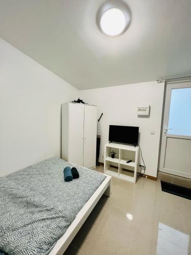 Habitación blanca con cama y TV en Gagny Charmant studio 16m2, en Gagny
