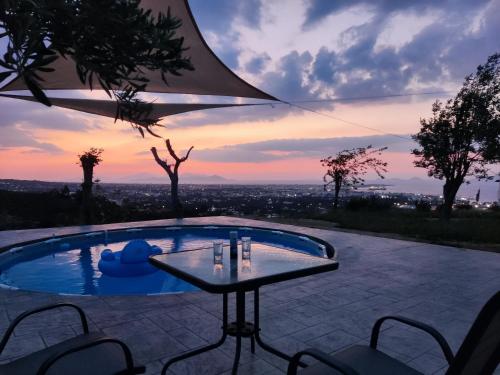 una piscina con tavolo e sedie e un tramonto di Yiorgos, amazing sunset view house a Psalidi