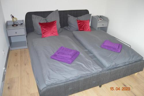 uma cama grande com lençóis roxos e almofadas vermelhas em Ferienwohnung Fillsack 