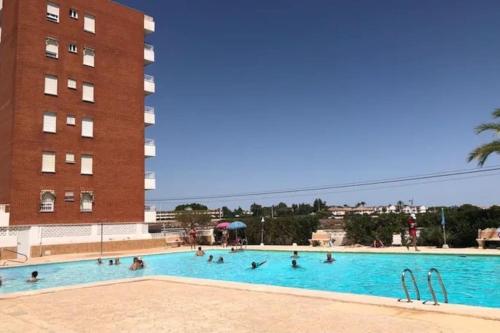 grupa ludzi w basenie obok budynku w obiekcie Modern penthouse with sea view w mieście Punta Prima