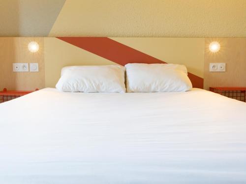 a large white bed with two pillows on it at ibis budget Tours Sud in Chambray-lès-Tours