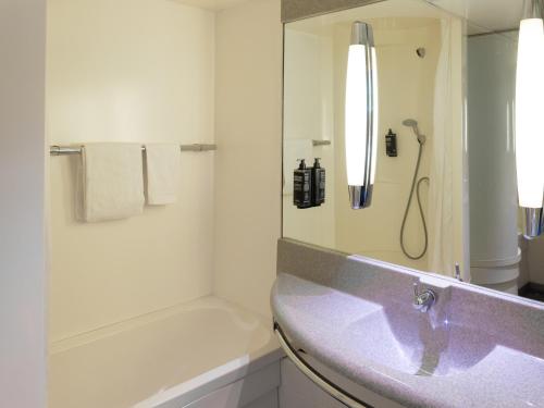 a white bathroom with a sink and a shower at ibis budget Tours Sud in Chambray-lès-Tours