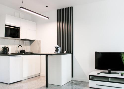 una cocina con mesa y TV. en Apartament White-Niska z garażem podziemnym, en Kielce