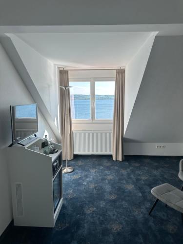 a living room with a large window and a television at Hotel Seegarten in Überlingen