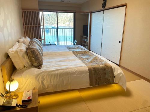 a bedroom with a large bed in a room with a balcony at 【CLUB DEEP BLUE】西伊豆　知る人ぞ知る美しい入江が眺める貸別荘！最大44人宿泊可能！ in Numazu