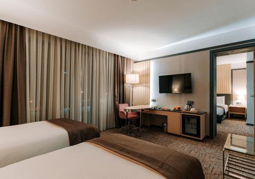 a hotel room with two beds and a desk at Invite Hotel Corner Trabzon in Trabzon