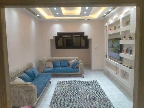 sala de estar con sofá azul y TV en شقة فندقية فاخرة بمصرالجديدة روكسى, en El Cairo