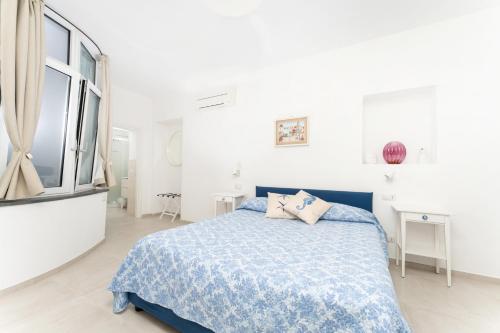 een witte slaapkamer met een blauw bed en een raam bij La casa di Bruna in Anacapri