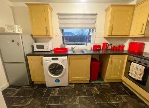 uma cozinha com uma máquina de lavar roupa e um micro-ondas em Cosy One Bedroom Flat in London em North Woolwich