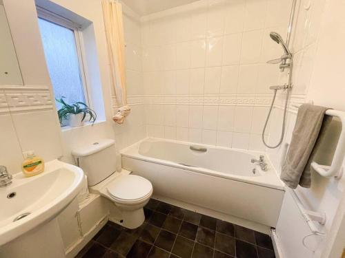 uma casa de banho com um WC, uma banheira e um lavatório. em Cosy One Bedroom Flat in London em North Woolwich