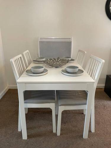 a white table with two chairs and bowls on it at Cosy One Bedroom Flat in London in North Woolwich