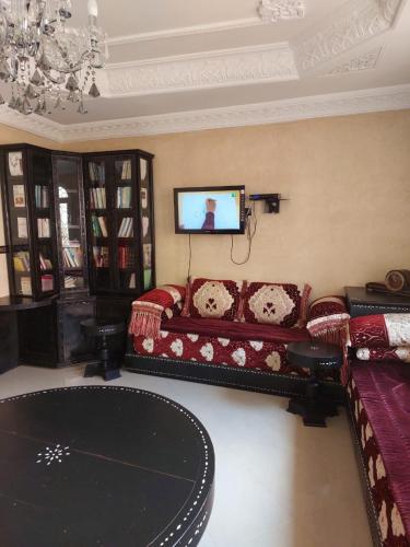 ein Wohnzimmer mit einem Sofa und einem Flachbild-TV in der Unterkunft Maison de charme in Tiznit