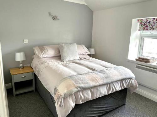 a bedroom with a bed with a night stand and a window at Cottage in Par, 4mi. from Fowey in Saint Blazey