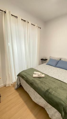a bedroom with a bed with white sheets and white curtains at Apartamento Retama Laguna Centro in Las Lagunas