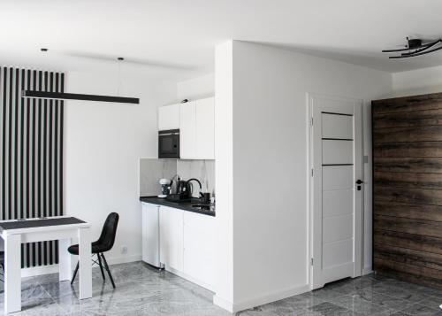 een keuken met witte kasten en een tafel en een stoel bij Apartament Black-Niska z garażem podziemnym in Kielce