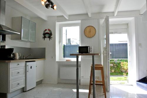 a kitchen with white cabinets and a clock on the wall at Sur le sentier des douaniers 3 in Ploubazlanec
