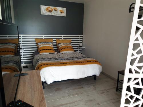 1 dormitorio con 1 cama con almohadas de color naranja y blanco en LE GÎTE DU CHEMIN ROUGE 