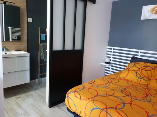 1 dormitorio con cama y lavamanos en LE GÎTE DU CHEMIN ROUGE 