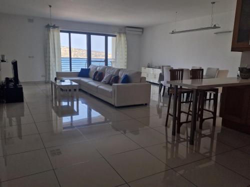 a living room with a couch and a table at Seafront apartment at Waters' Edge in St Paul's Bay