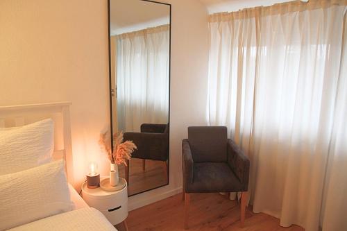 a bedroom with a mirror and a chair and a bed at Chiemsee Apartments in Altenmarkt an der Alz