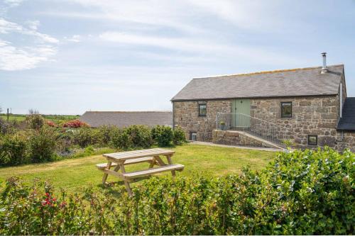 a picnic bench in front of a stone house at Cosy cottage, walk to Porthcurno beach, Pedn Vouder, Minack & PK Museum in Penzance