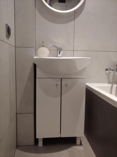 a white bathroom with a sink and a mirror at Mazur in Kalisz