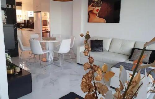 salon z białą kanapą, stołem i krzesłami w obiekcie Modern penthouse with sea view w mieście Punta Prima