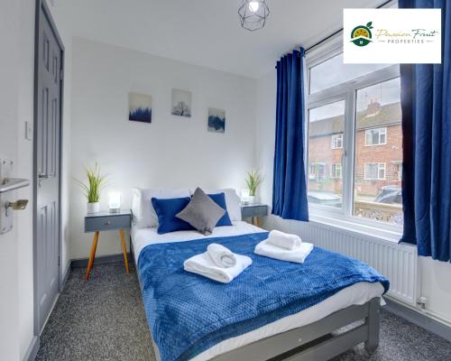 Un dormitorio con una cama azul con toallas. en 5 Bedroom - 5 Bathroom house close to Coventry City Centre with spacious kitchen Free Wi-fi and garden - 56HRC en Coventry