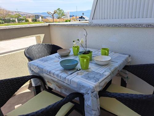 a table on a balcony with bowls and cups on it at Apartments Fran in Baška