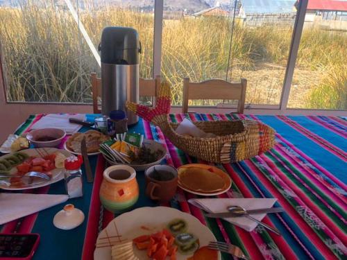 uma mesa com comida em cima de uma toalha de mesa azul em Uros TITIKAKA the Best lodge em Puno