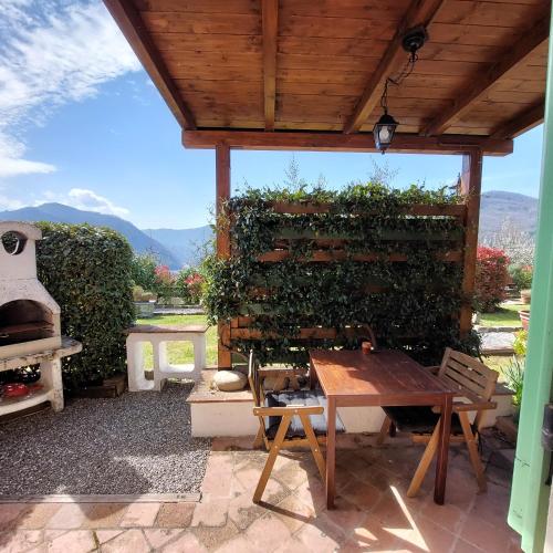 a patio with a wooden table and a green wall at Agriturismo Tenuta La Fratta in Bagni di Lucca