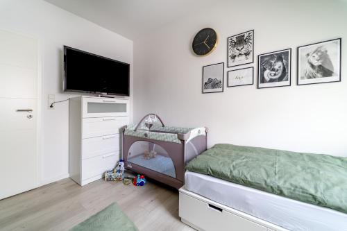 a bedroom with a crib and a flat screen tv at FEWO am Schwanenteich mit Dachterrasse - Innenstadt in Emden