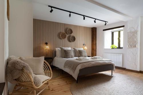 a bedroom with a bed and a chair at Naut Retreat, The Big Barn - Spacious & cosy cottage, walk to Porthcurno beach, Pedn Vouder & Minack Theatre in Penzance