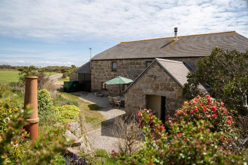 a stone building with a patio and a garden at Porthcurno Barns, The Big Barn - Spacious & cosy cottage, walk to Porthcurno beach, Pedn Vouder & Minack Theatre in Penzance