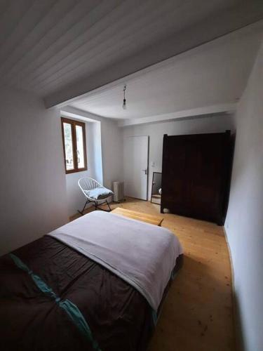 a bedroom with a bed and a chair in a room at Logement Sainte-Énimie in Sainte-Énimie