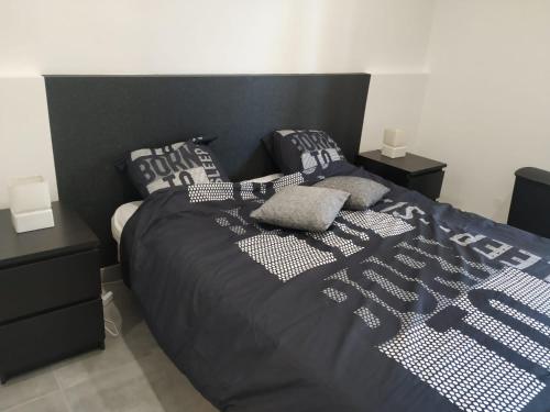 a bed with a black comforter and pillows on it at Résidence Odalys Saint Loup Appartement Climatisé entierement rénové in Cap d'Agde