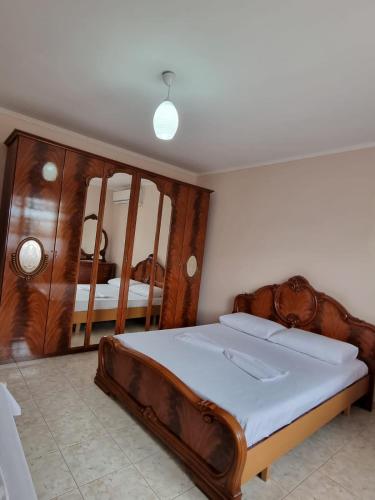 a bedroom with a large wooden bed and a mirror at Zani GuestHouse in Fier