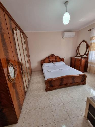 1 dormitorio con cama de madera y reloj en la pared en Zani GuestHouse en Fier