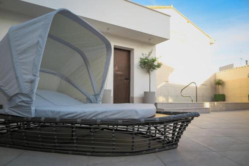 a wicker bed with a cover on a patio at Tomé, casa de huéspedes in Orgaz