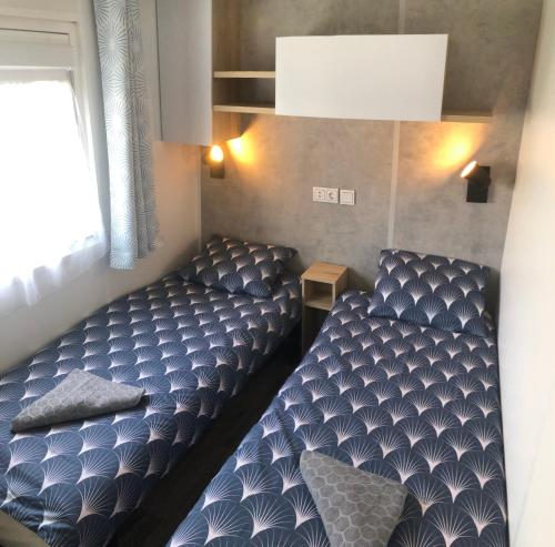 um pequeno quarto com uma cama e uma janela em Mobile Home de standing em Canet-en-Roussillon