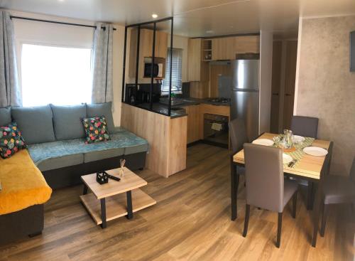 a living room with a couch and a table and a kitchen at Mobile Home de standing in Canet-en-Roussillon