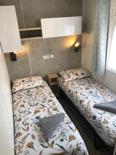 Habitación pequeña con 2 camas y ventana en Mobile Home de standing, en Canet-en-Roussillon